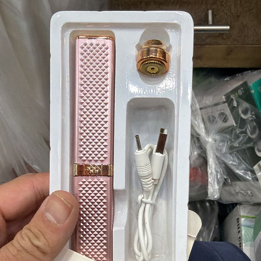 Pink facial and eyebrow hair remover in packaging held by a hand.