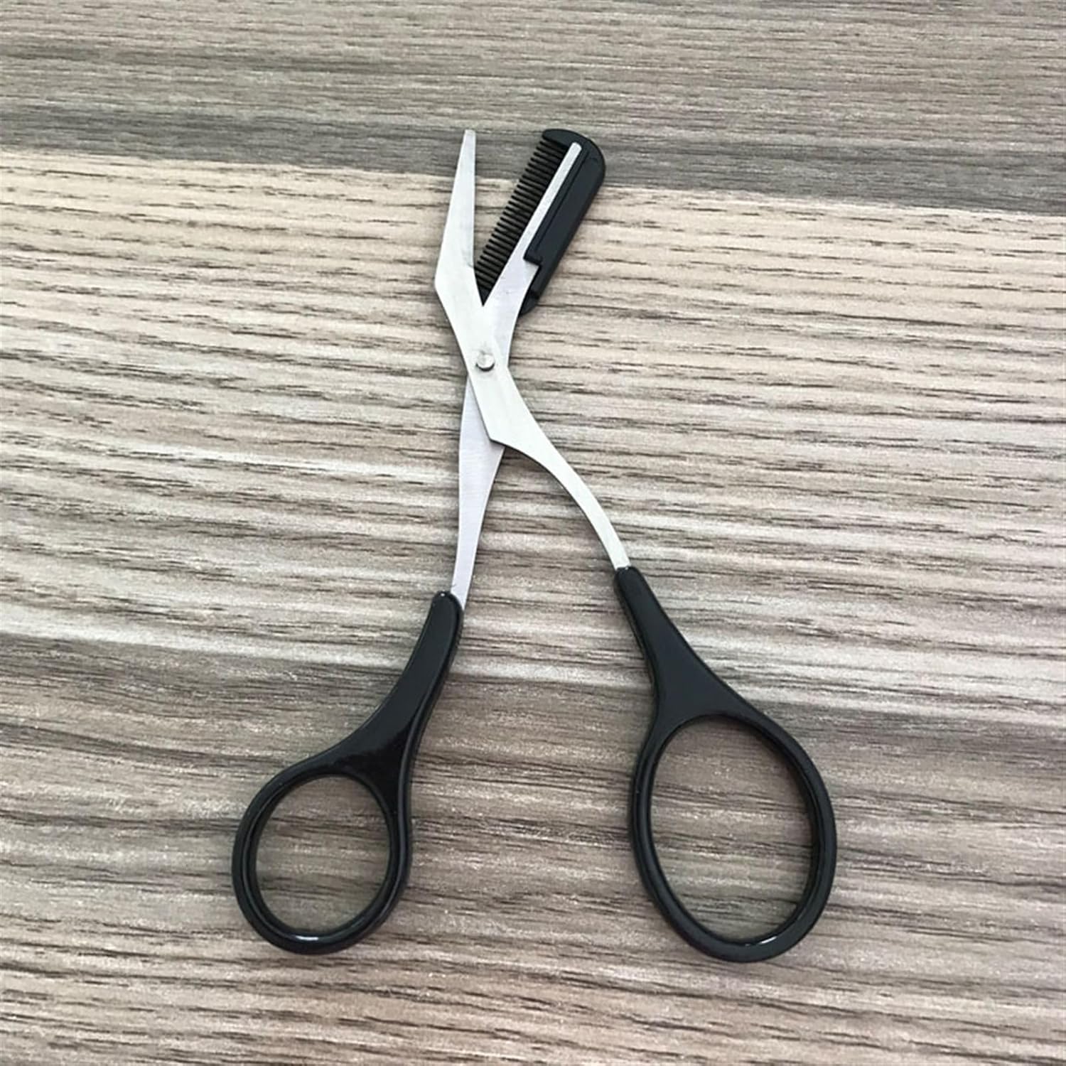 Hair cutting shears with a comb on a wooden surface