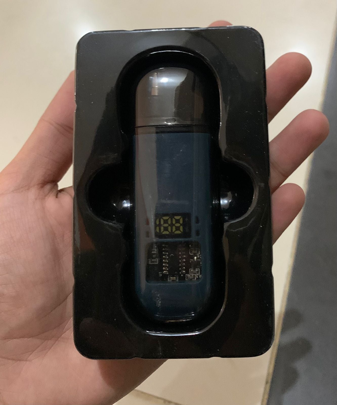 Digital thermometer in a black holder held by a hand against a neutral background
